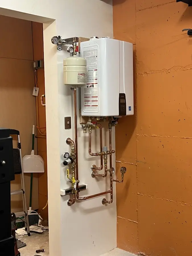 Plumbing technician inspecting water heater connections in Port Jefferson